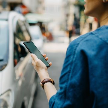 Woman ordering a taxi ride with mobile app on smartphone in the city