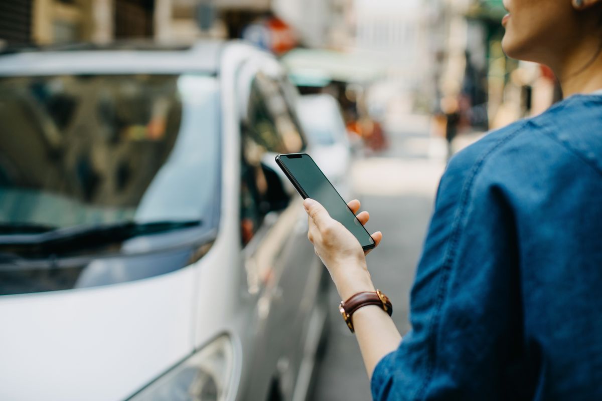 Woman ordering a taxi ride with mobile app on smartphone in the city