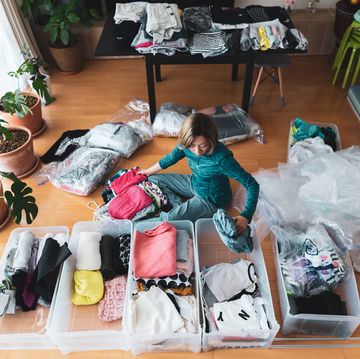 woman organizes clothes in living room of her home