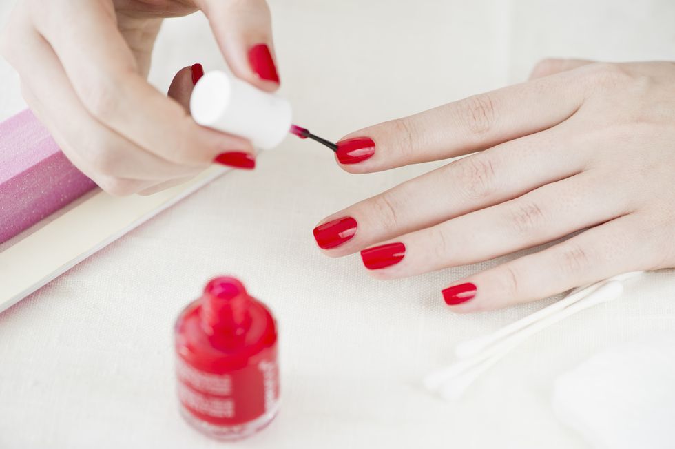 Woman painting her nails with red nail polish