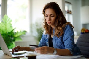 woman looking at card while using computer