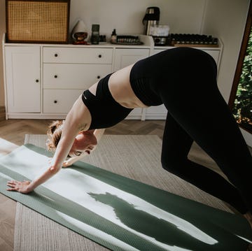 a woman performs the downwards dog yoga  pilates position on a exercise mat