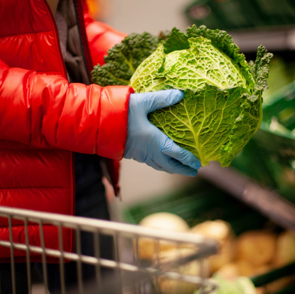 Woman picking out savoy cabbage at the supermarket, wearing protective gloves woman picking out savoy cabbage at the supermarket, wearing protective gloves