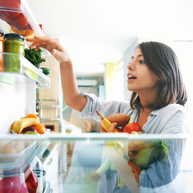 woman picking up some fruits and veggies from the fridge