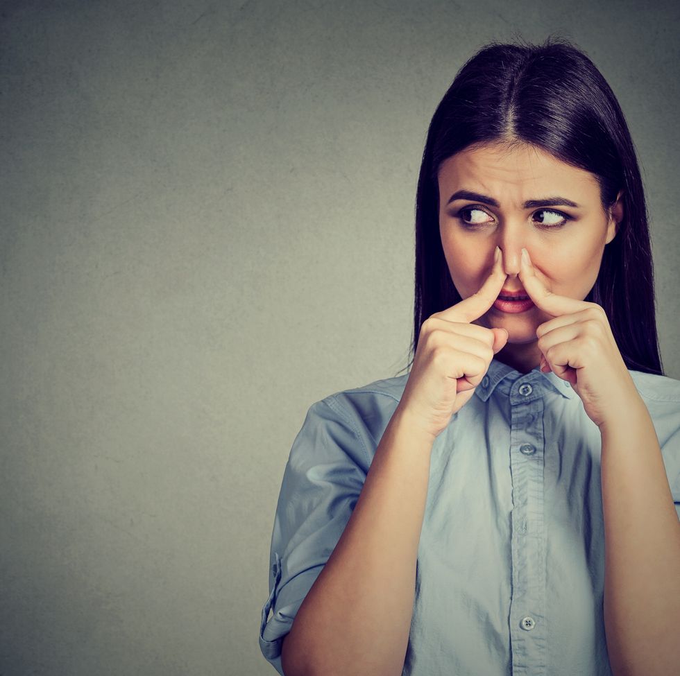 woman pinches nose with fingers looks with disgust away something stinks bad smell