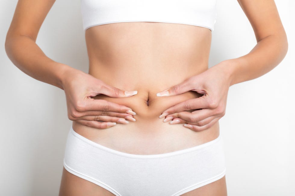 woman pinching her stomach on white background