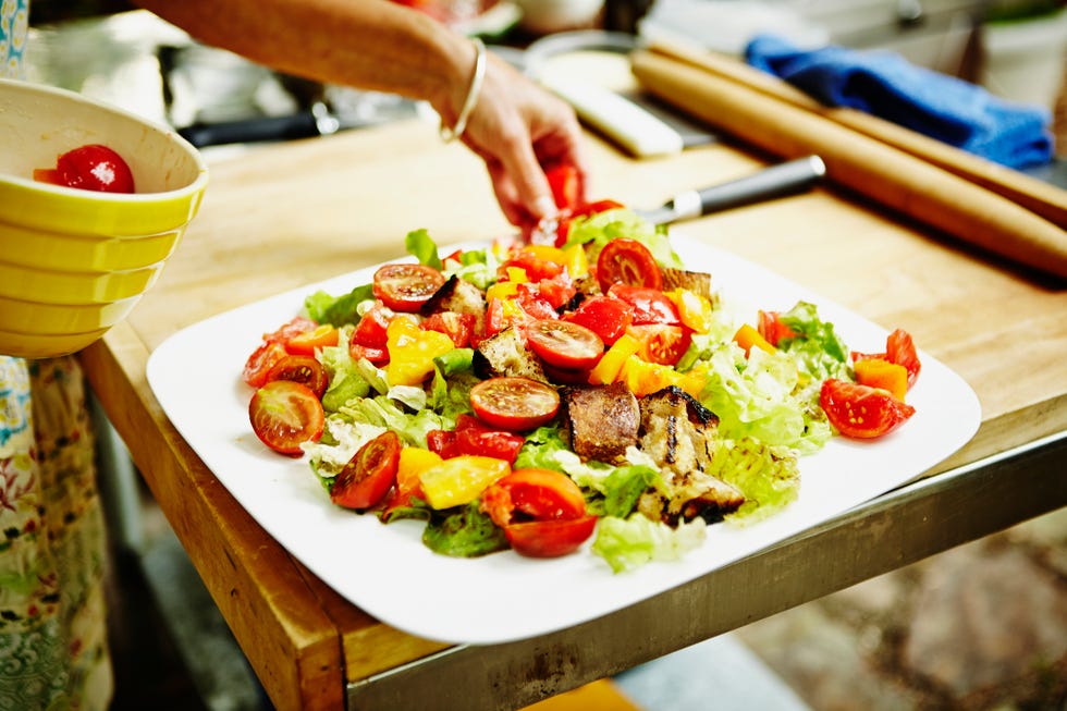 Woman placing heirloom tomatoes on salad