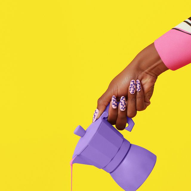 studio shot of a hand pouring a pink liquid from a purple coffee pot into a cup