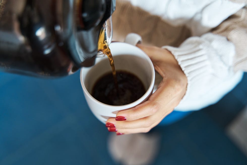 a woman pouring hot coffee into a cup