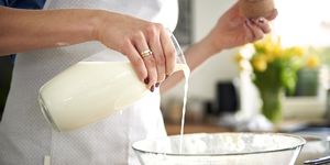 woman pouring milk into mixing bowl in kitchen