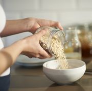 woman pouring oats into bowl in kitchen close up