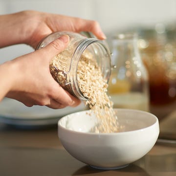 Woman pouring oats into bowl in kitchen, close up. woman pouring oats into bowl in kitchen, close up