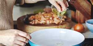 woman pouring olive oil into the skillet