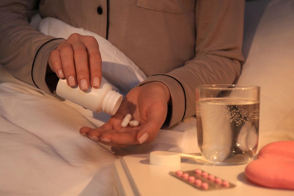 woman pouring pills from bottle into hand indoors, closeup insomnia treatment