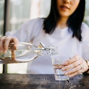 woman pouring water from bottle into the glass at a outdoor cafe