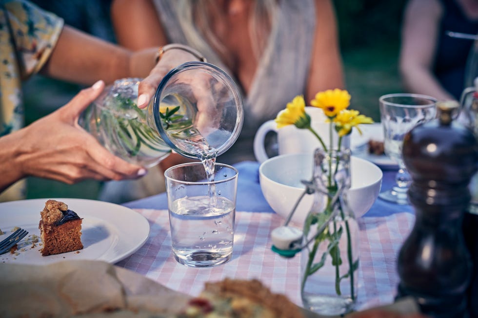 woman pouring water into a glass at garden party