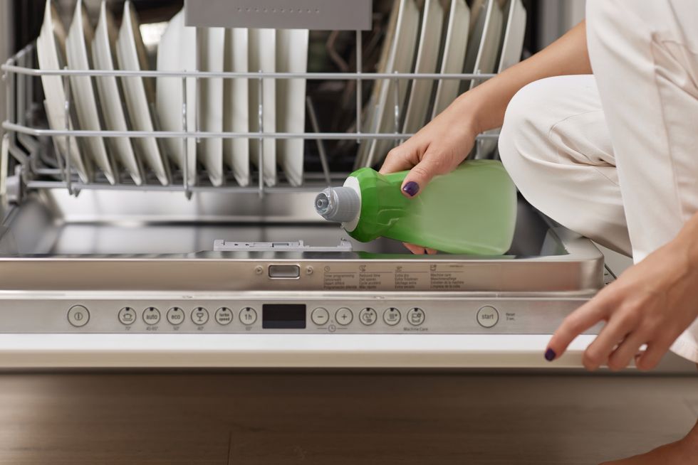 woman pours rinse aid into the dishwasher compartment