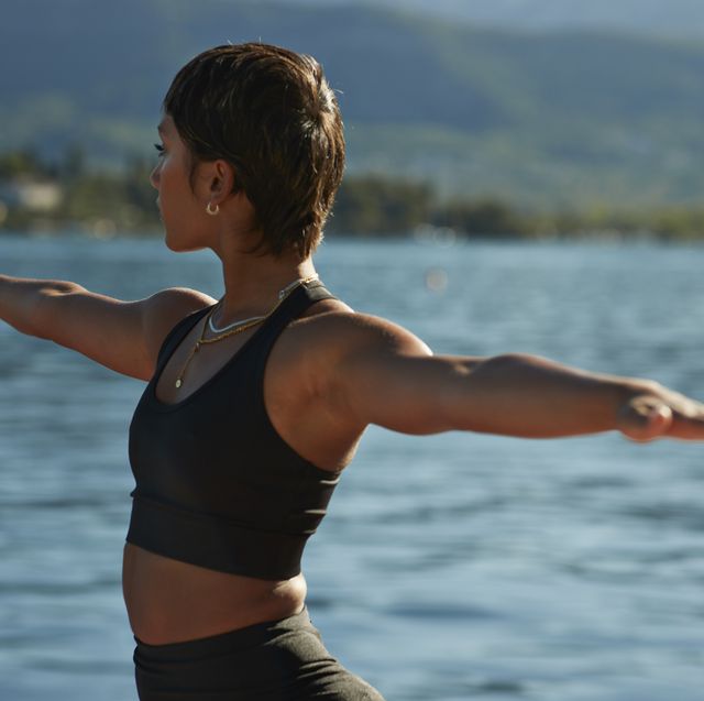 woman practicing warrior pose against bay