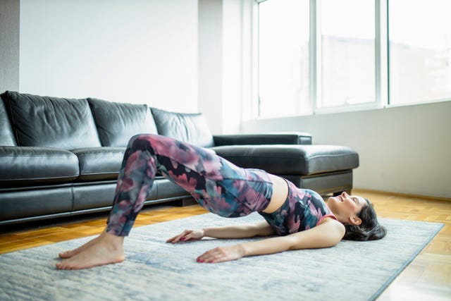 woman practicing yoga, doing glute bridge exercise, dvi pada pithasana at home