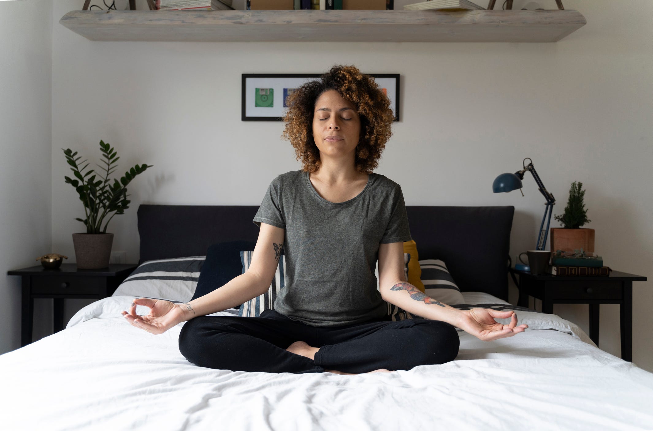 Woman practicing yoga, sitting on bed, meditating