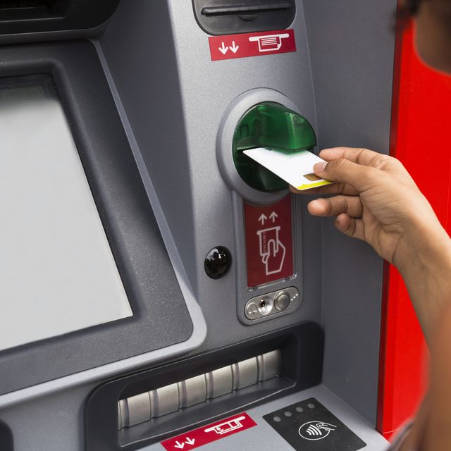 Woman pushing credit card at cash dispenser, partial view