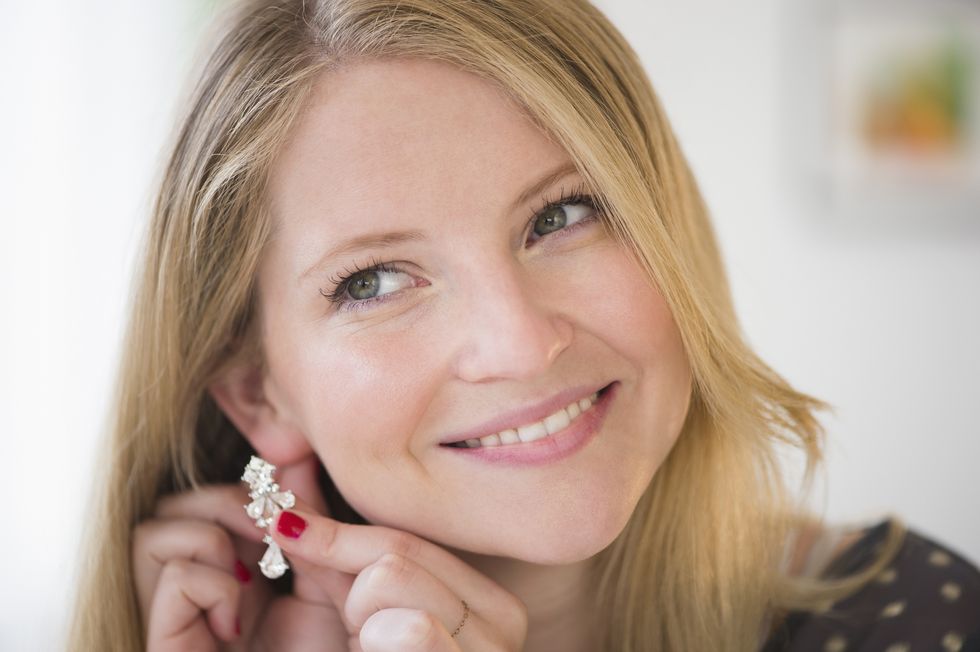 woman putting on earring, smiling