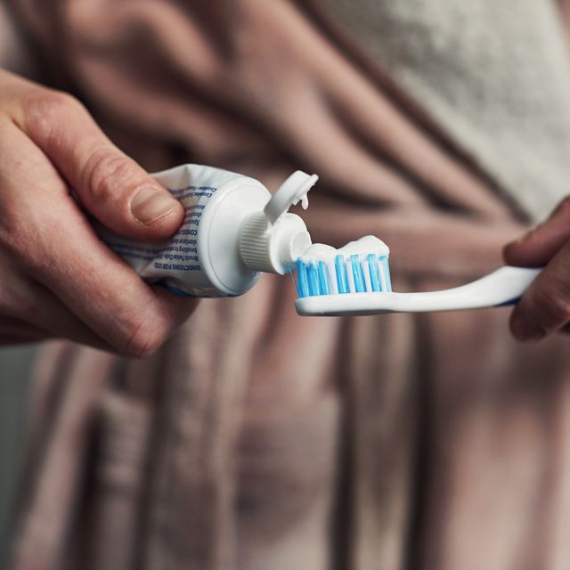 woman putting toothpaste on a toothbrush