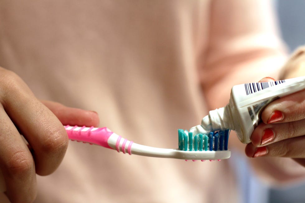 woman putting toothpaste on toothbrush