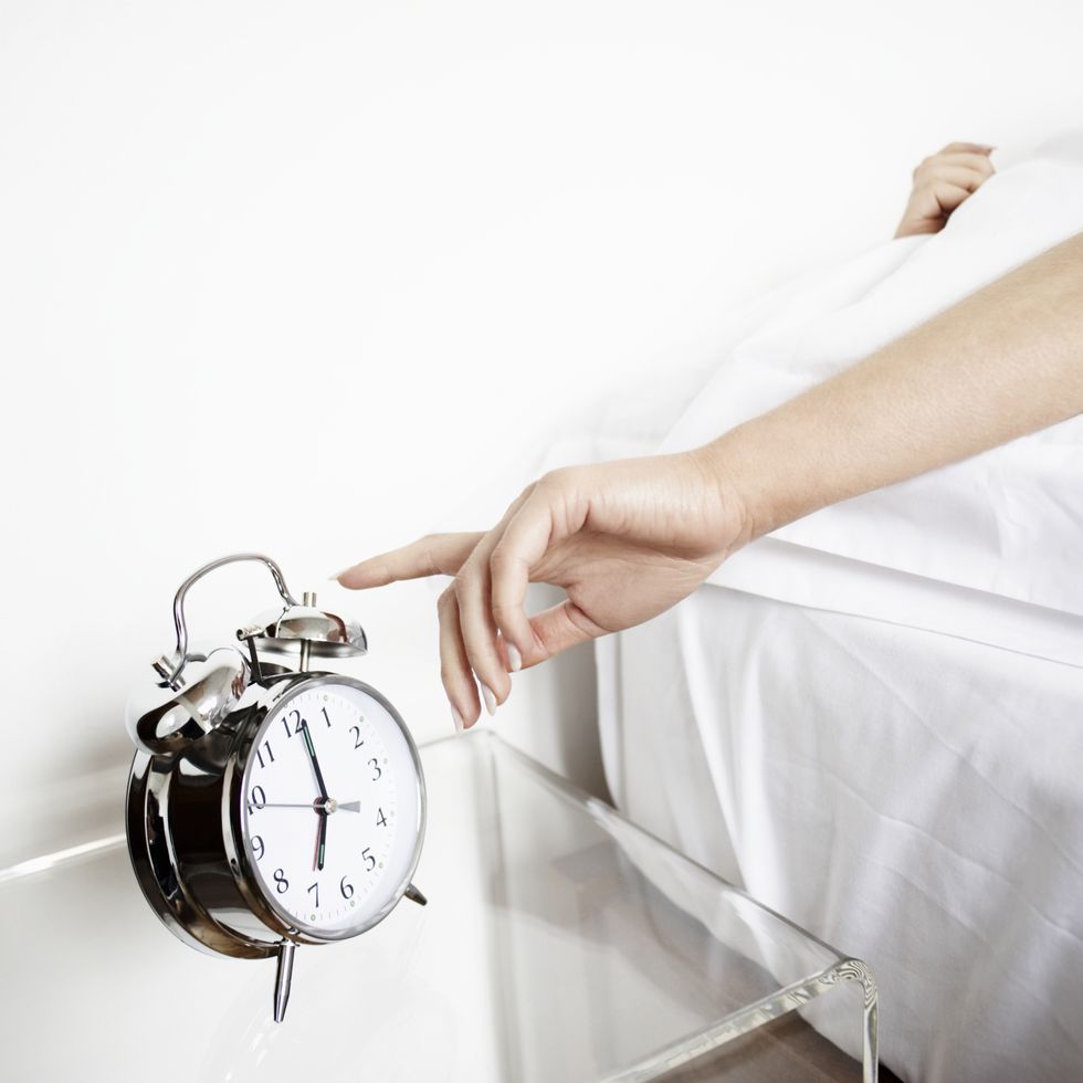 woman reaching to turn off alarm clock