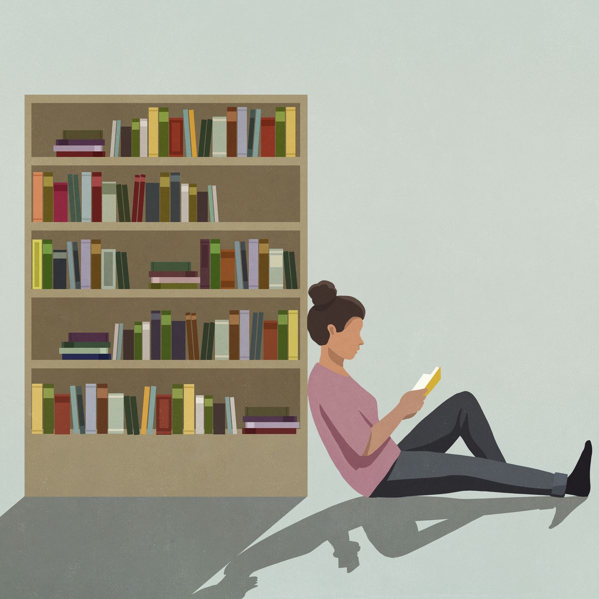 woman reading book against bookcase