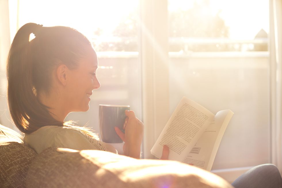 woman reading book and drinking coffee