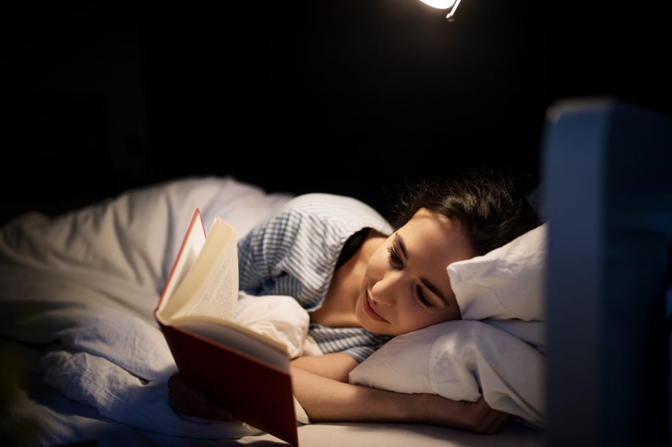 woman reading book in bed