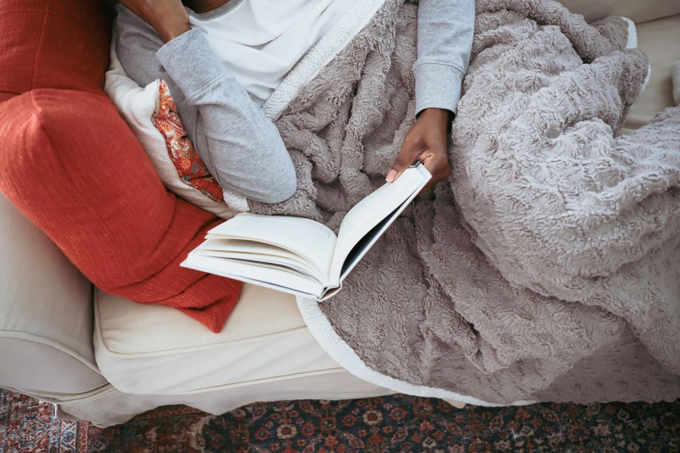 ソファに横たわり本を読む女性