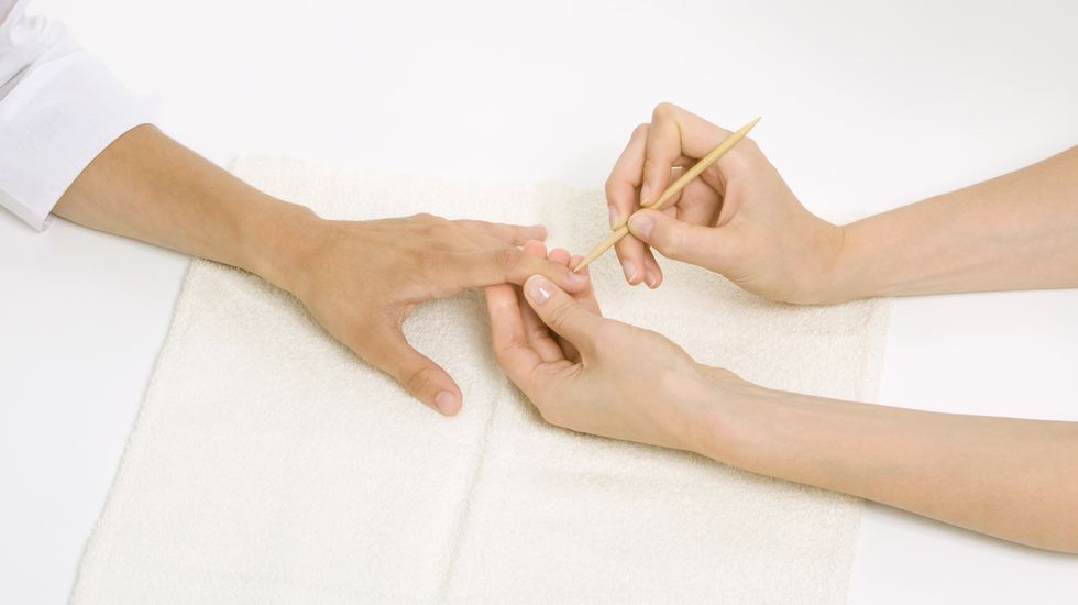 woman receiving manicure, looking down at hand, cropped view