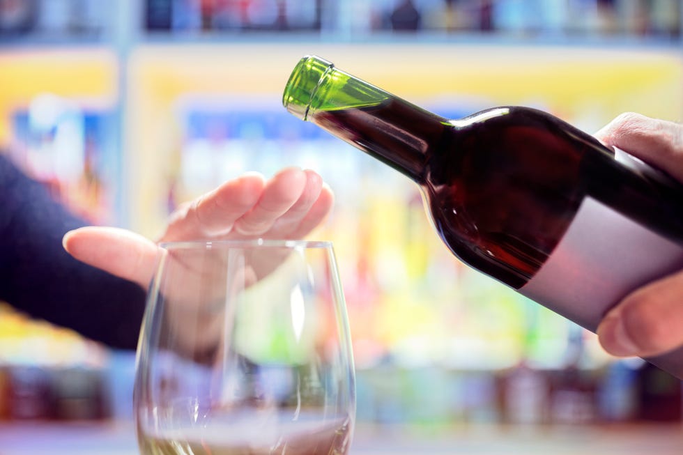 Woman rejecting more alcohol from wine bottle in bar