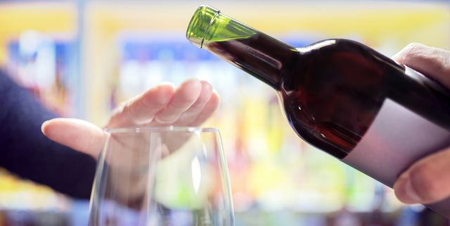 Woman rejecting more alcohol from wine bottle in bar