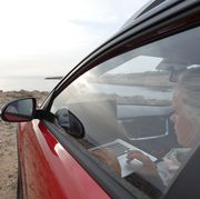 woman relaxes in car near edge of sea