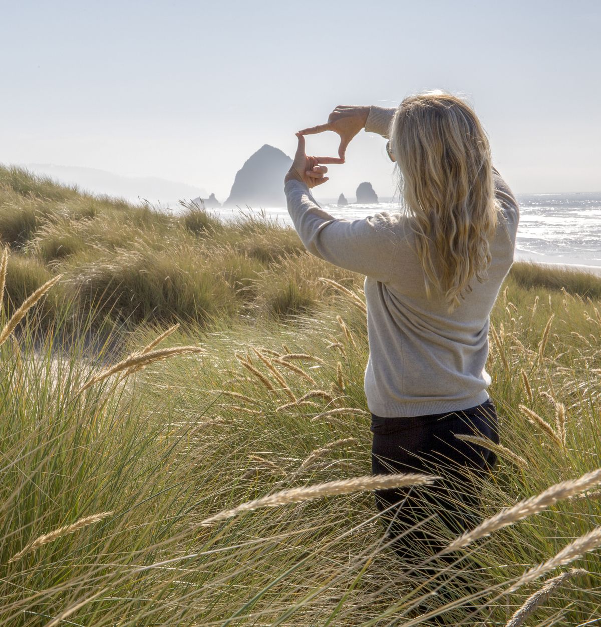 woman relaxes in grassy meadow on coastline in the morning