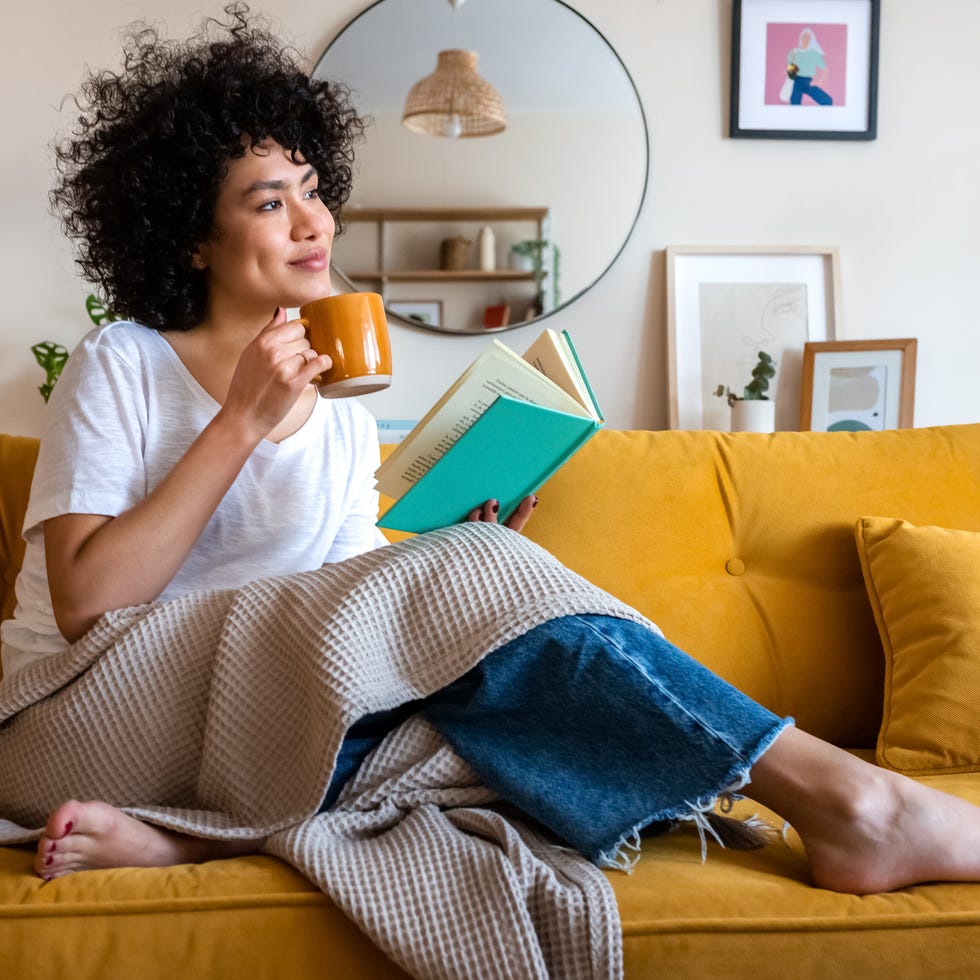 Self-care ideas woman relaxing on a couch with a cup of tea