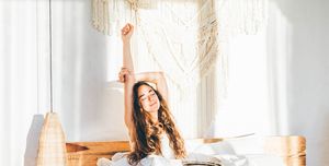 woman relaxing on a bed woman stretching hands in bed