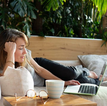 woman relaxing on sofa, watching a movie on laptop