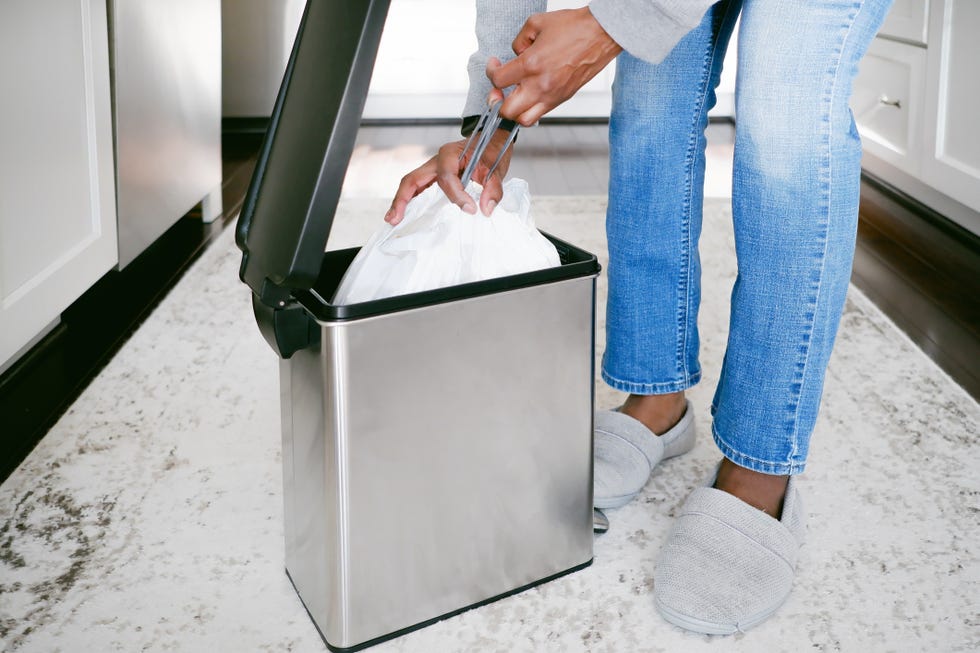 woman removes trash bag from can