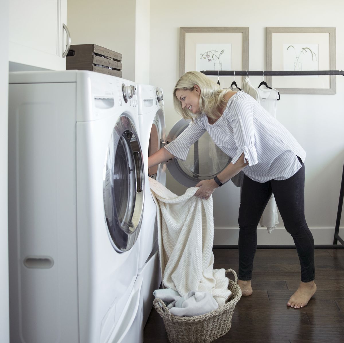 Woman removing laundry from dryer in laundry room