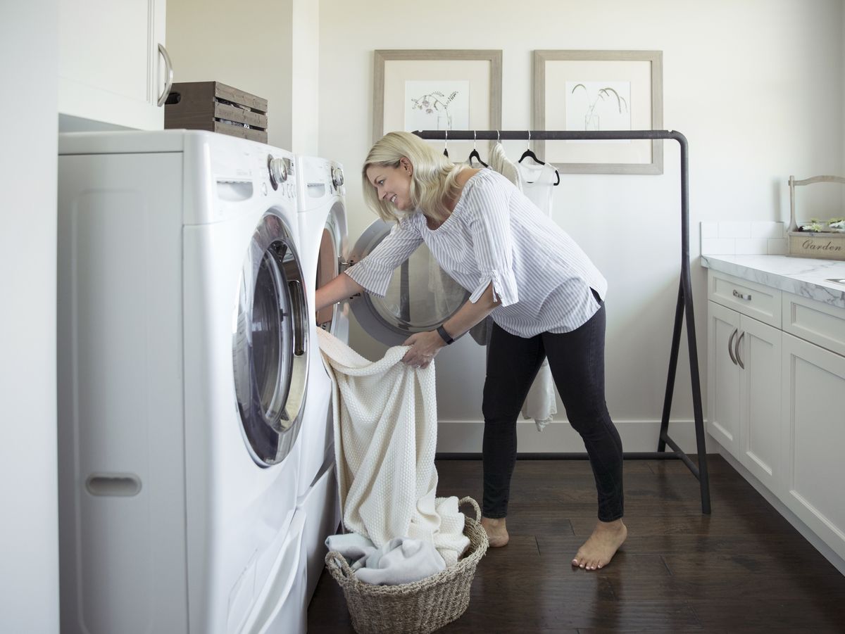 https://hips.hearstapps.com/hmg-prod/images/woman-removing-laundry-from-dryer-in-laundry-room-royalty-free-image-915093676-1556661060.jpg?crop=0.88847xw:1xh;center,top&resize=1200:*