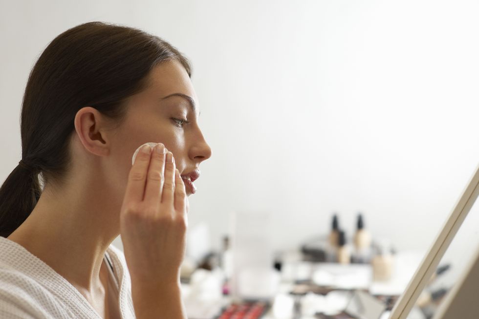 woman removing make up with products in background