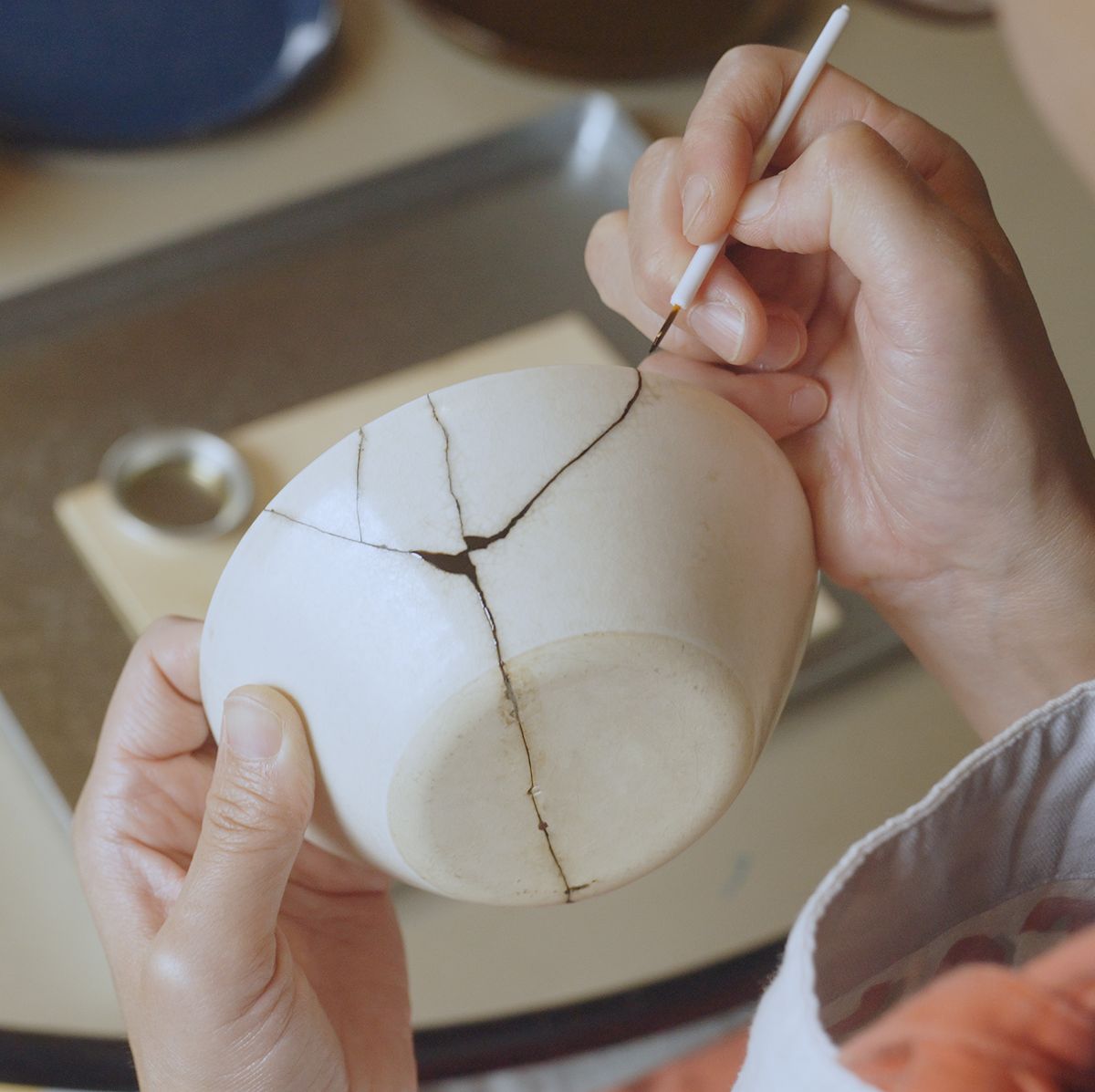 woman repairing broken pottery kintsugi