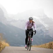 a woman rides her road bike along the trans canada trail bikepath near canmore, alberta, canada