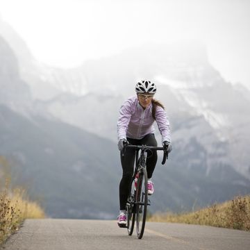 a woman rides her road bike along the trans canada trail bikepath near canmore, alberta, canada