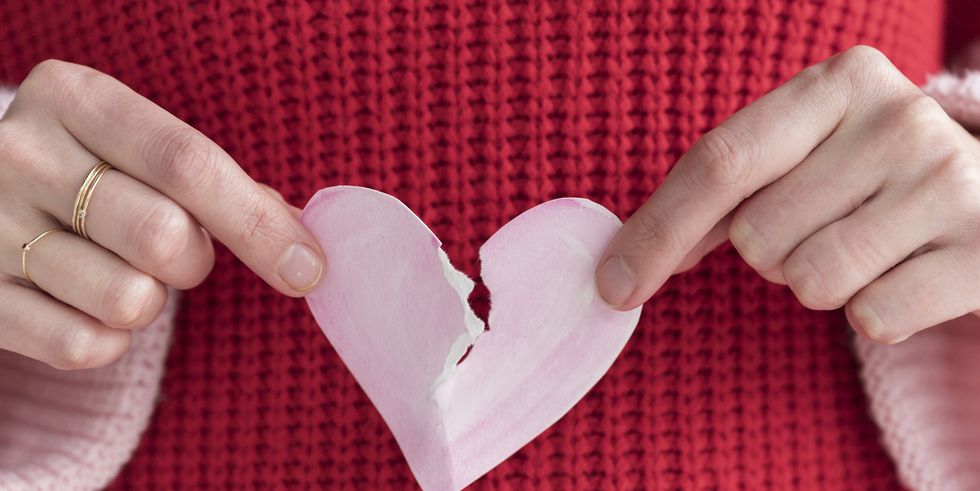 woman ripping paper heart in half