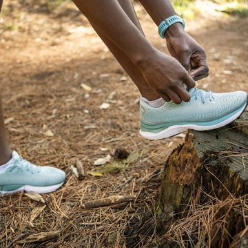 woman runner tying her shoelaces before going for a run on forest trail